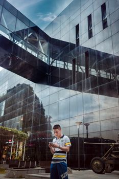 A man walking by a modern glass building, reflecting the vibrant city life.