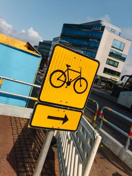 黄色自行车十字路口标志指示自行车路线，背景为城市景观
