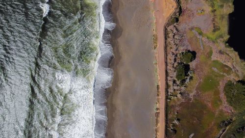Free A stunning aerial image capturing Pacifica's coastline with ocean waves and lush greenery. Stock Photo