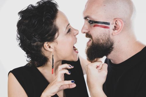 Free A modern couple playfully interacting with artistic face paint in a creative portrait setting. Vibrant and fun mood. Stock Photo