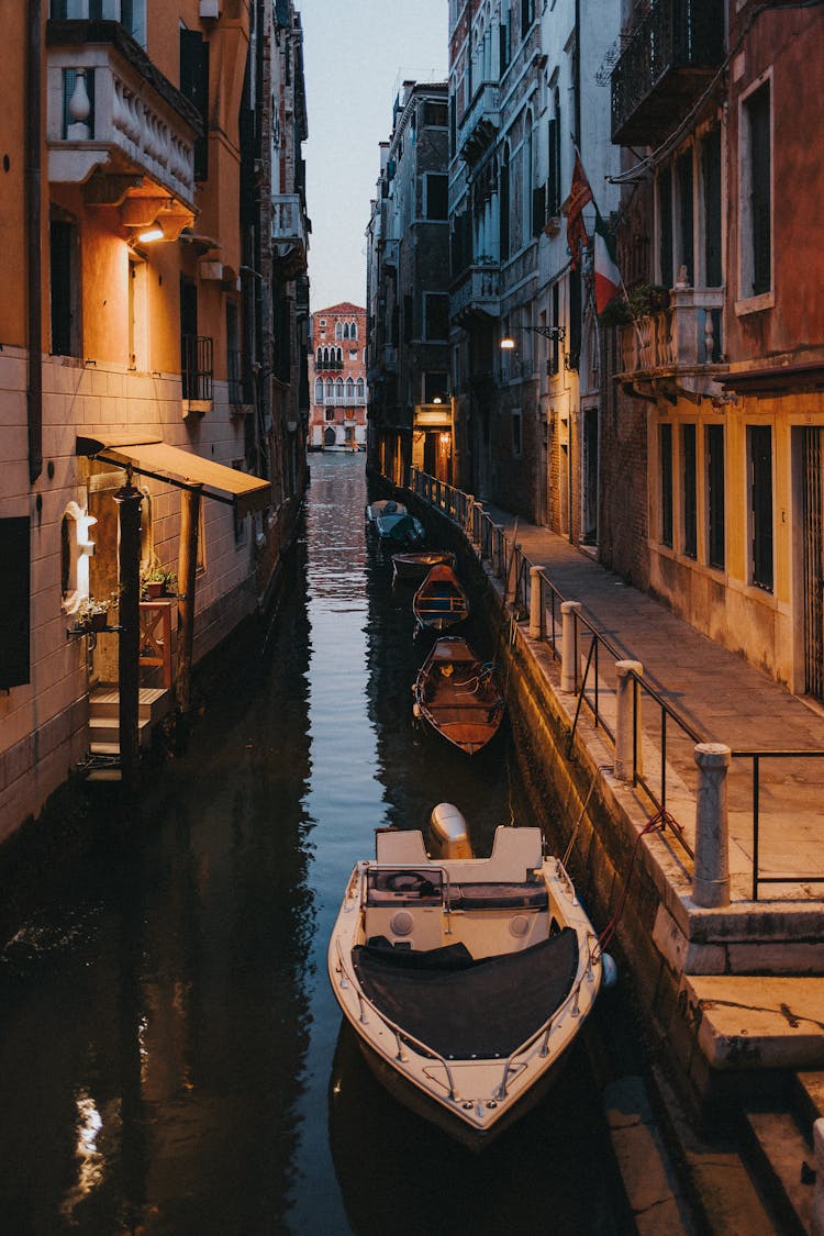 White Boat On River Between Brown Concrete Buildings