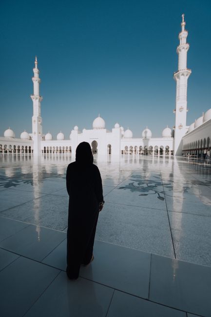 Silhouette of a woman in hijab standing at the Sheikh Zayed Grand Mosque in Abu Dhabi.