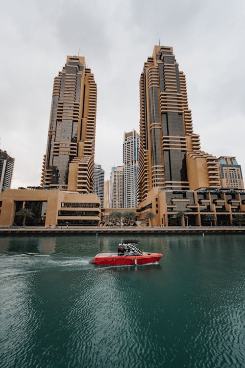 都市の建物の近くの水に赤と白のボート