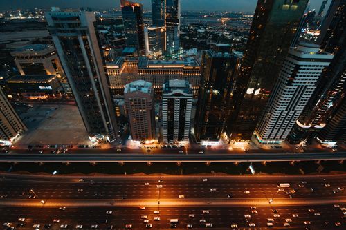 Free A vibrant urban skyline with illuminated skyscrapers and busy roads captured from above at night. Stock Photo