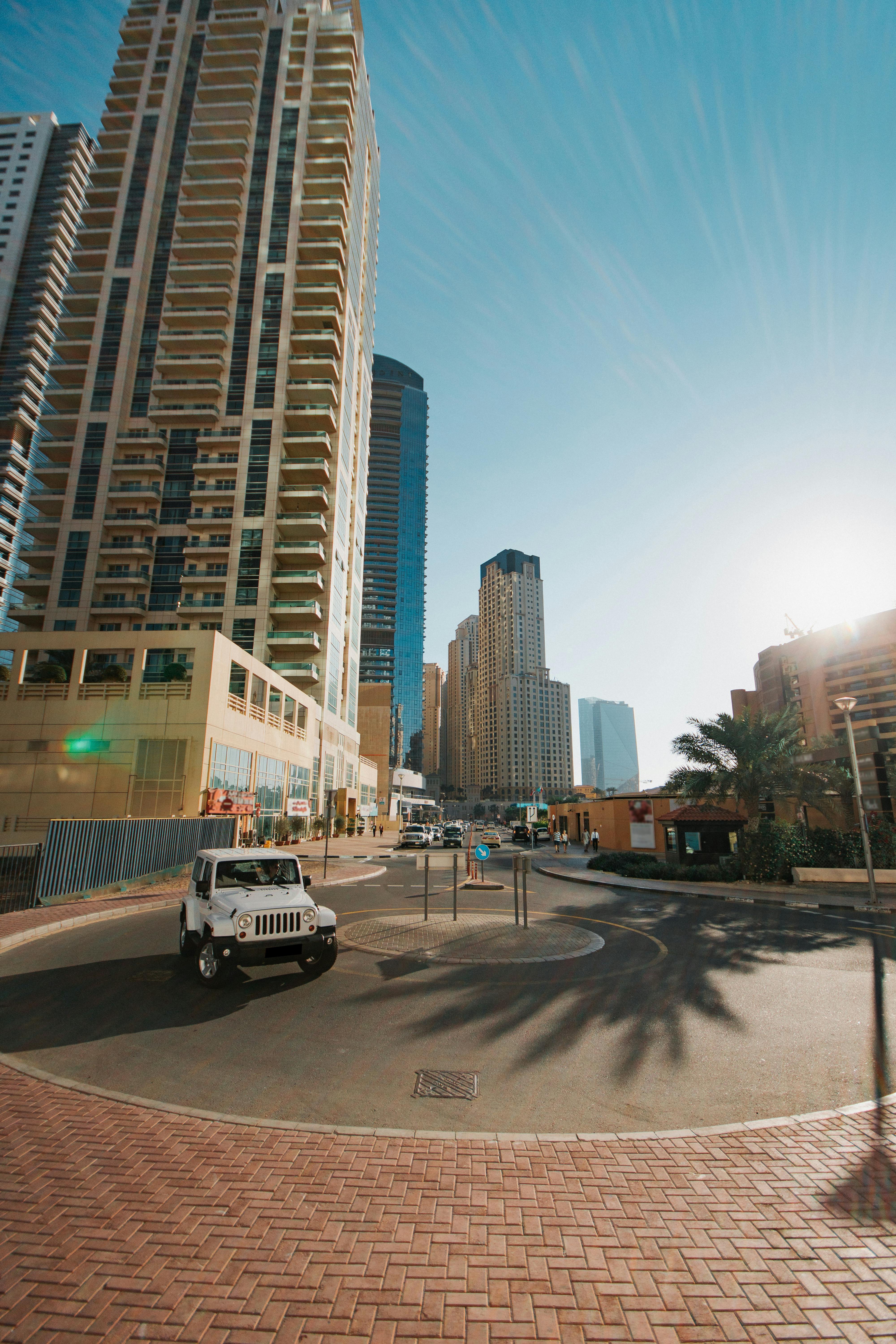 现代城市的街景中，摩天大楼矗立在明亮的阳光下，路上车辆川流不息