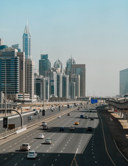 Free Skyscrapers tower over a busy highway in Dubai under a clear blue sky. Stock Photo