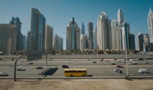 阳光明媚的高速公路上车辆行驶，映衬着迪拜码头摩天大楼的全景