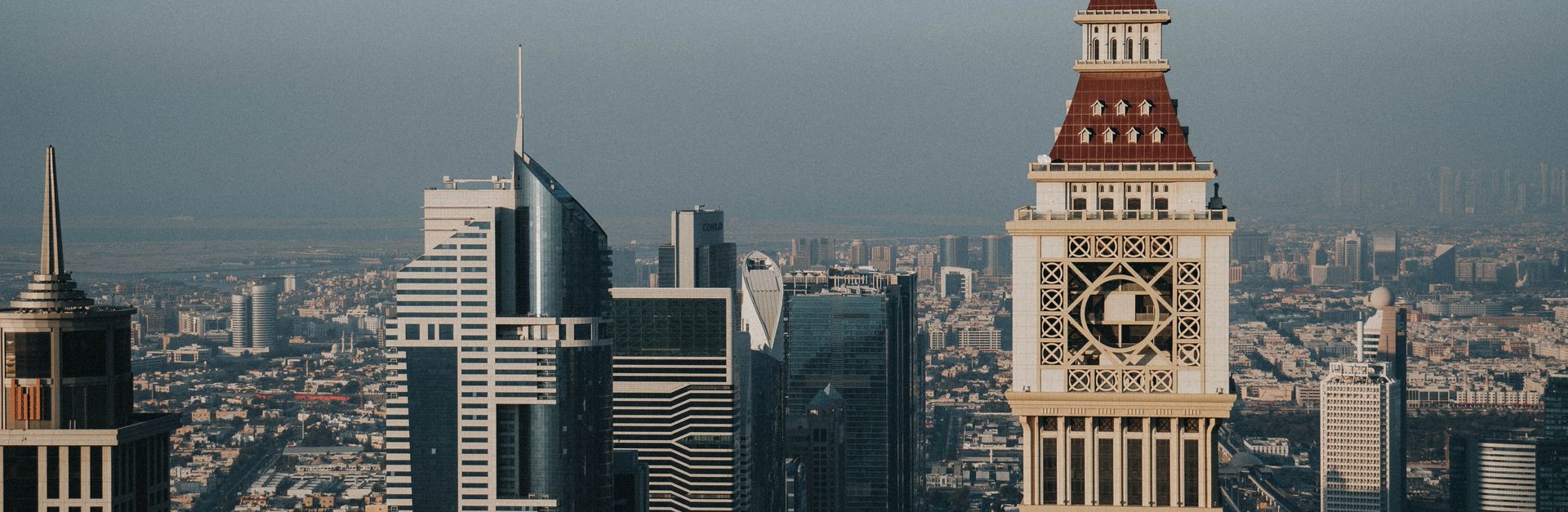 Aerial view of Dubai's iconic skyline with Al Yaqoub Tower and modern skyscrapers under a clear sky.