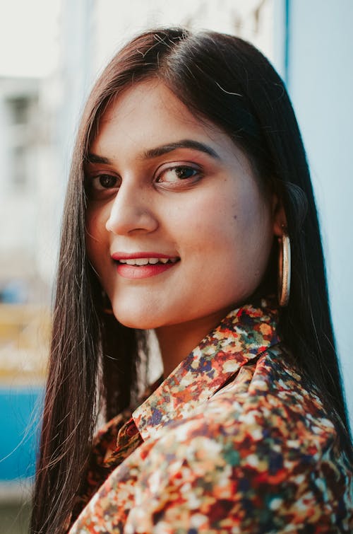 Free Side view of positive ethnic female with long dark straight hair and earrings looking at camera Stock Photo