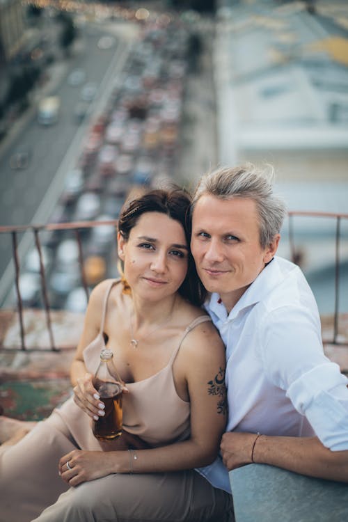 High angle of happy couple sitting close and hugging while looking at camera during date