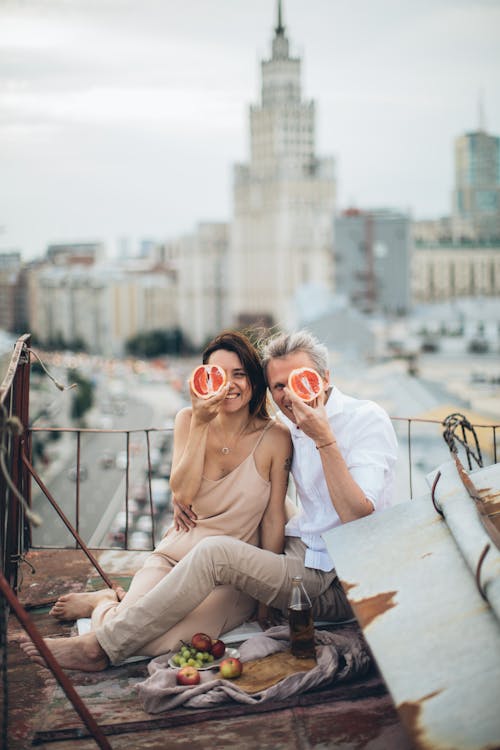 Full body of cheerful couple in casual outfits having fun or rooftop during date