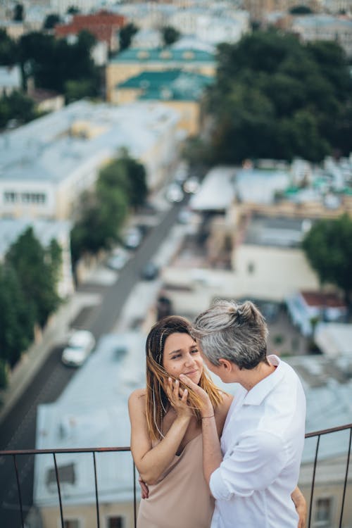 High angle of romantic couple hugging on terrace while smiling and looking at each other