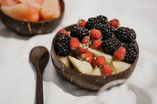 A close-up of blackberries and raspberries with citrus in a coconut bowl, perfect for healthy eating.