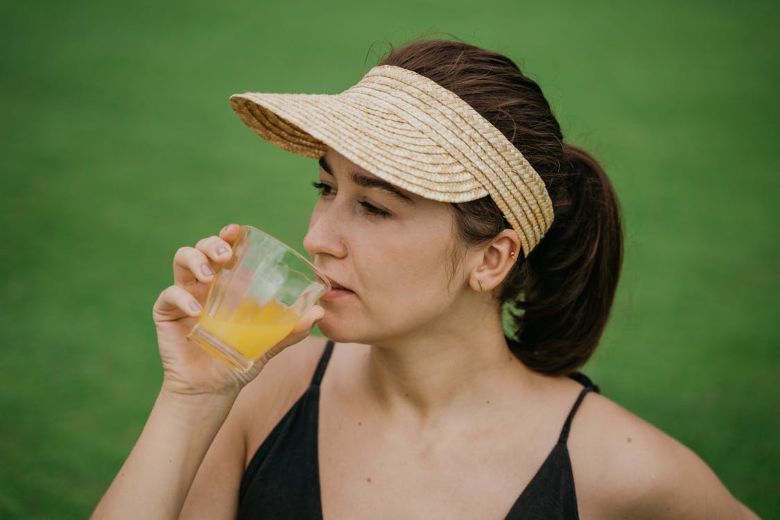 Woman in Black Tank Top Drinking from Clear Glass