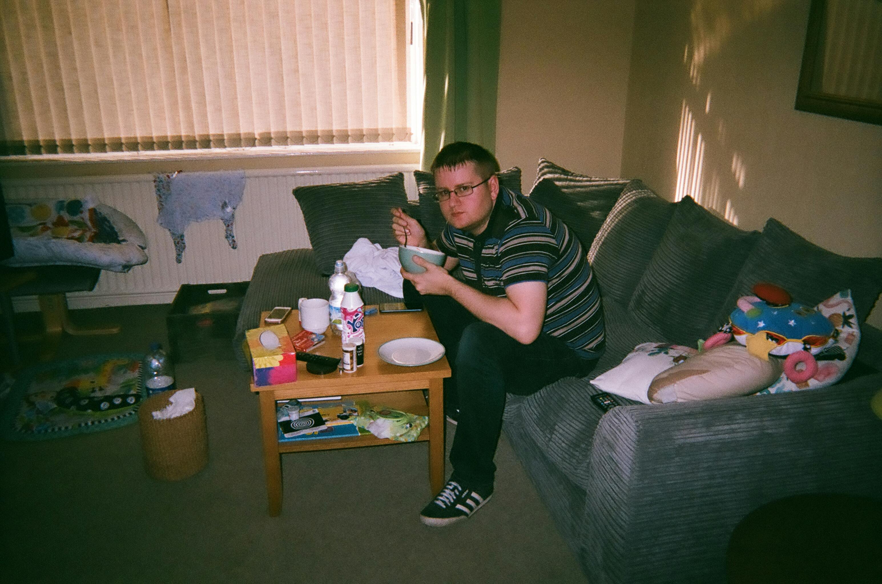 man in striped polo shirt sitting on a couch while sitting