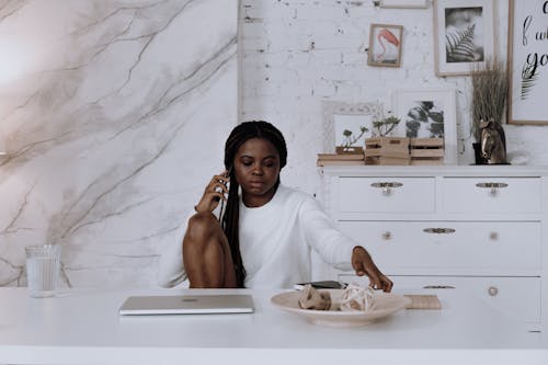 Woman in White Long Sleeve Shirt Sitting on White Bed