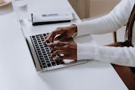 在现代家庭办公环境中，一双女性正在笔记本电脑上打字的双手特写