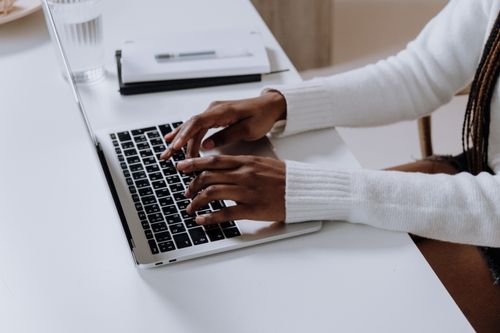 Free Close-up of woman's hands typing on a laptop in a modern home office setting. Stock Photo