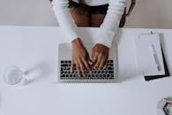 一名女子在家庭办公室的现代环境中，头顶视角拍摄她正在笔记本电脑上打字