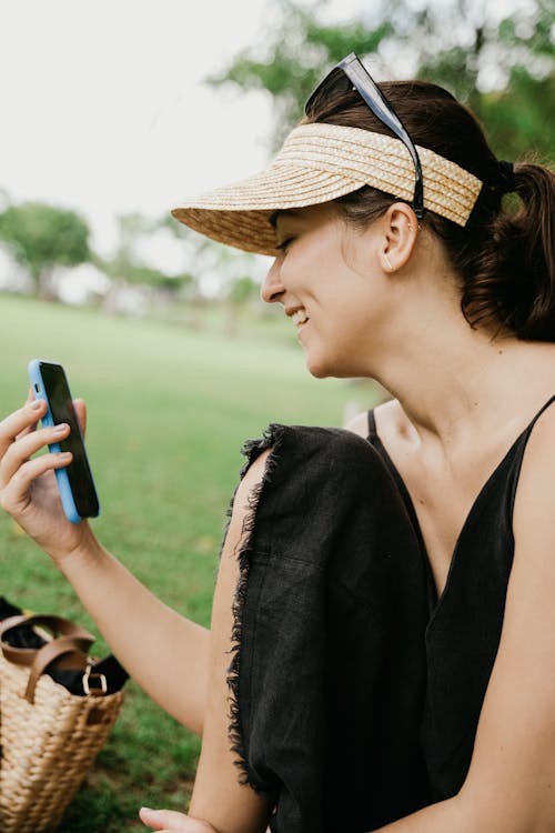 Woman in Black Tank Top Holding Blue Smartphone