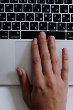 Close-up of a hand on a laptop with a Cyrillic keyboard. Modern tech in use.