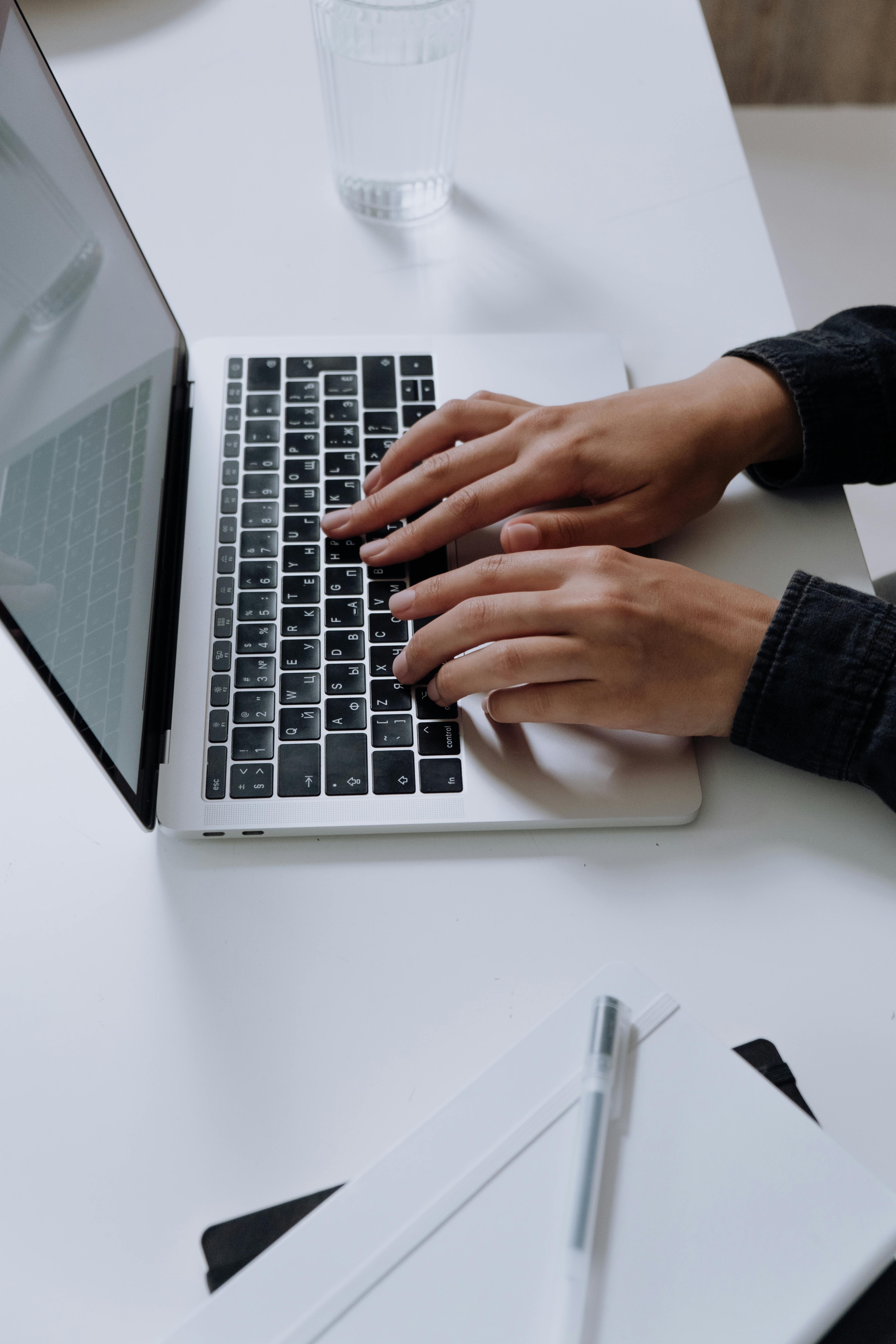 person using macbook pro on white table