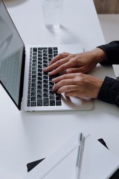 A person typing on a laptop keyboard in an office setting, showcasing modern technology and productivity.
