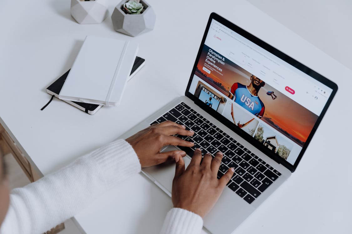 Free Person Using a Macbook Pro on a White Table Stock Photo