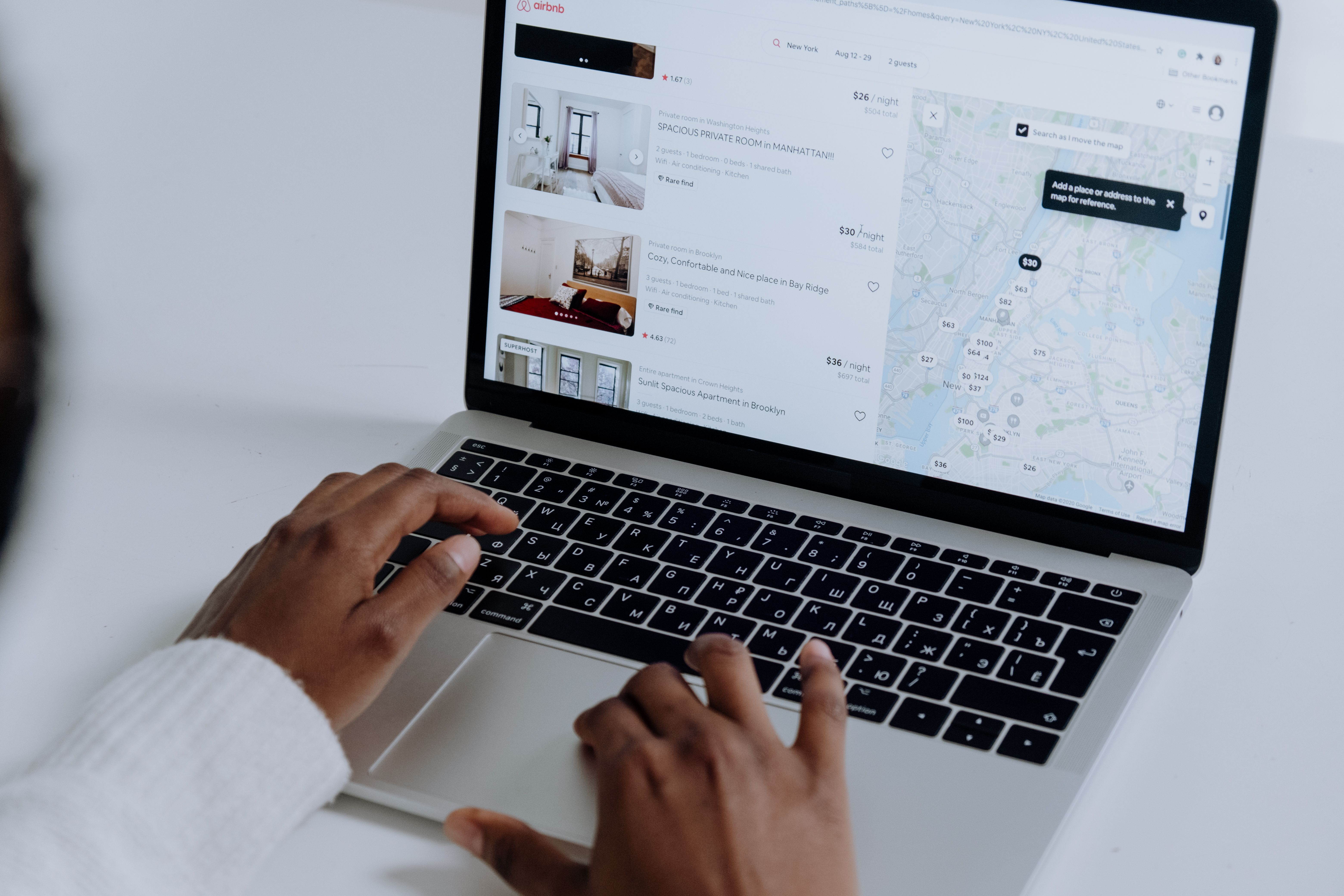 Person browsing holiday rental listings on a laptop, comparing accommodation options on a map