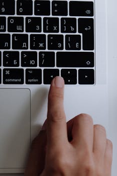 A detail shot of a hand typing on a modern laptop keyboard with a focus on technology and interaction.