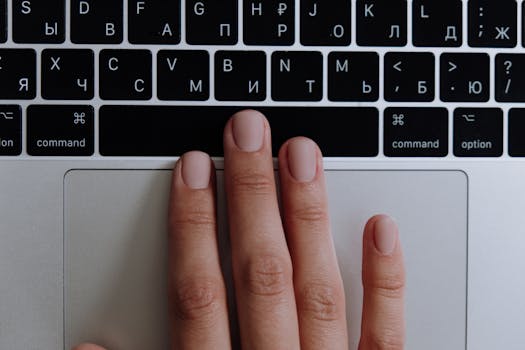 A close-up of a hand typing on a silver laptop with a Russian keyboard layout, showcasing modern technology.