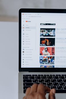 Person browsing YouTube videos on a laptop, showcasing modern technology and online content.