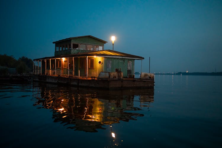 Brown Wooden House On Water During Night Time