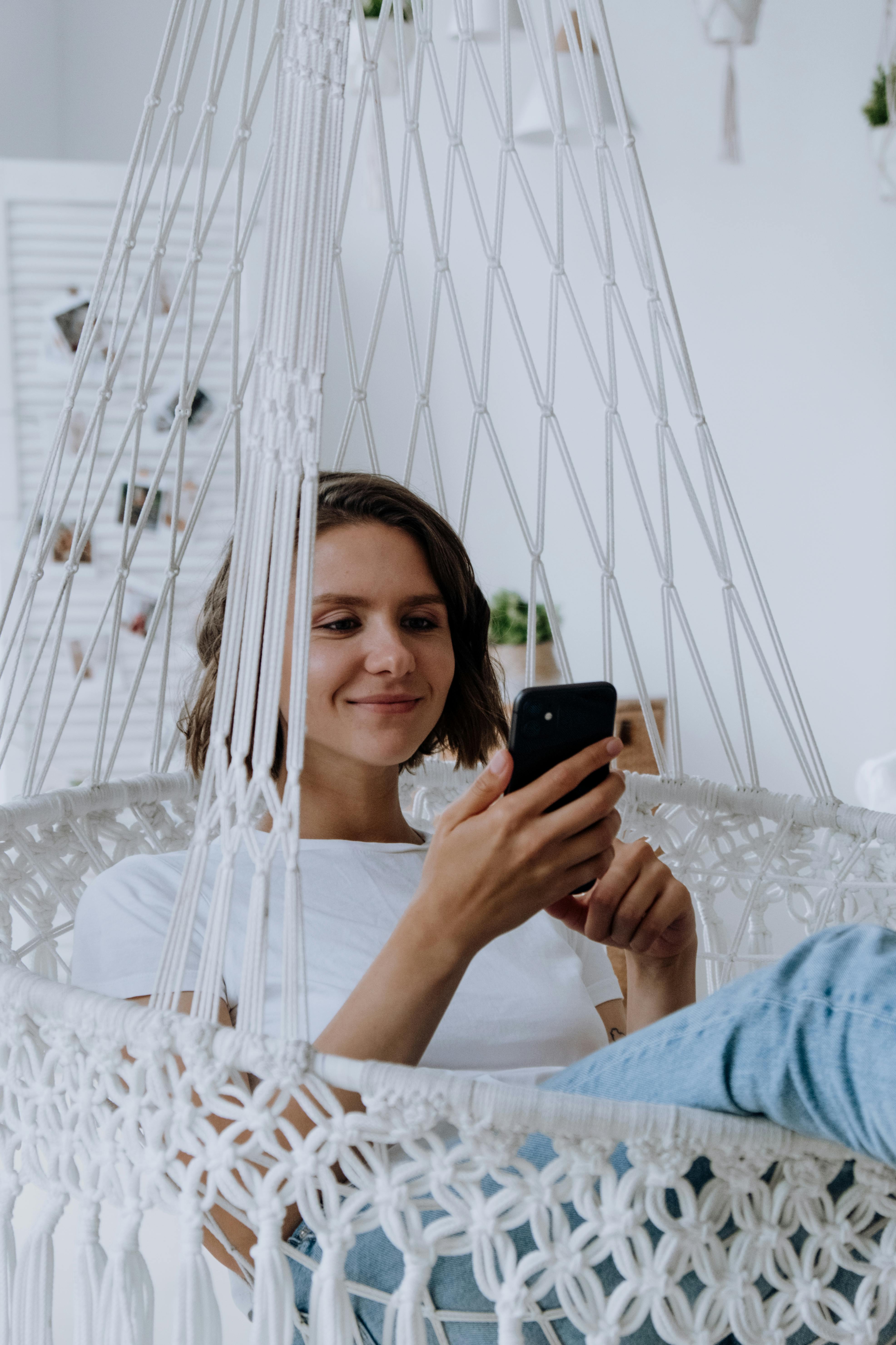 woman in white dress holding black smartphone