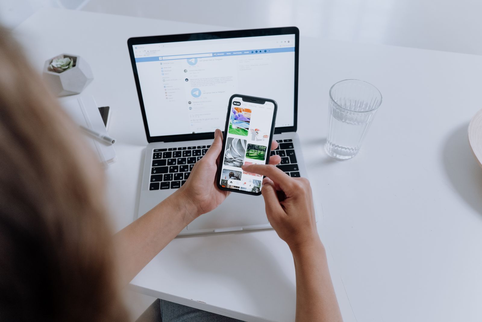 A person using a smartphone and a laptop at the same time