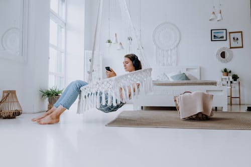 Free Woman in White and Blue Long Sleeve Shirt and Blue Denim Jeans Lying on White Bed Stock Photo