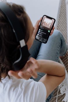 在舒适的环境中戴着耳机用智能手机听音乐的人