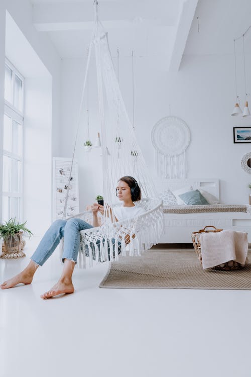 Girl in White Shirt and Blue Denim Jeans Sitting on White Sofa Chair