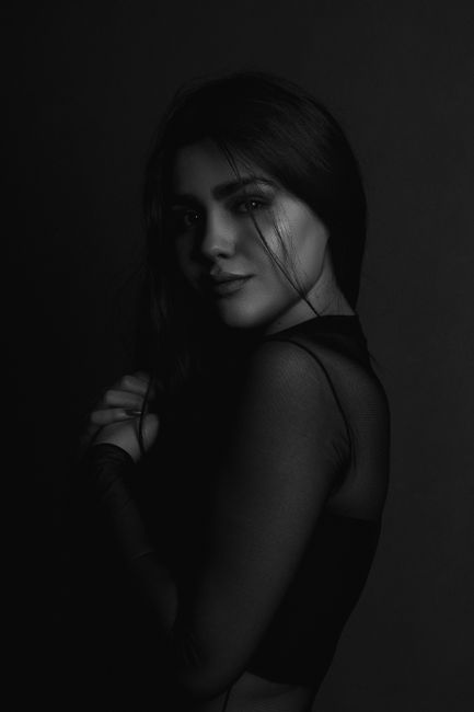 Graceful black and white portrait of a woman in a Parisian studio, highlighting her elegance and poise.