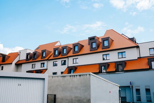 A contemporary residential building with vibrant orange roofs under a clear blue sky.