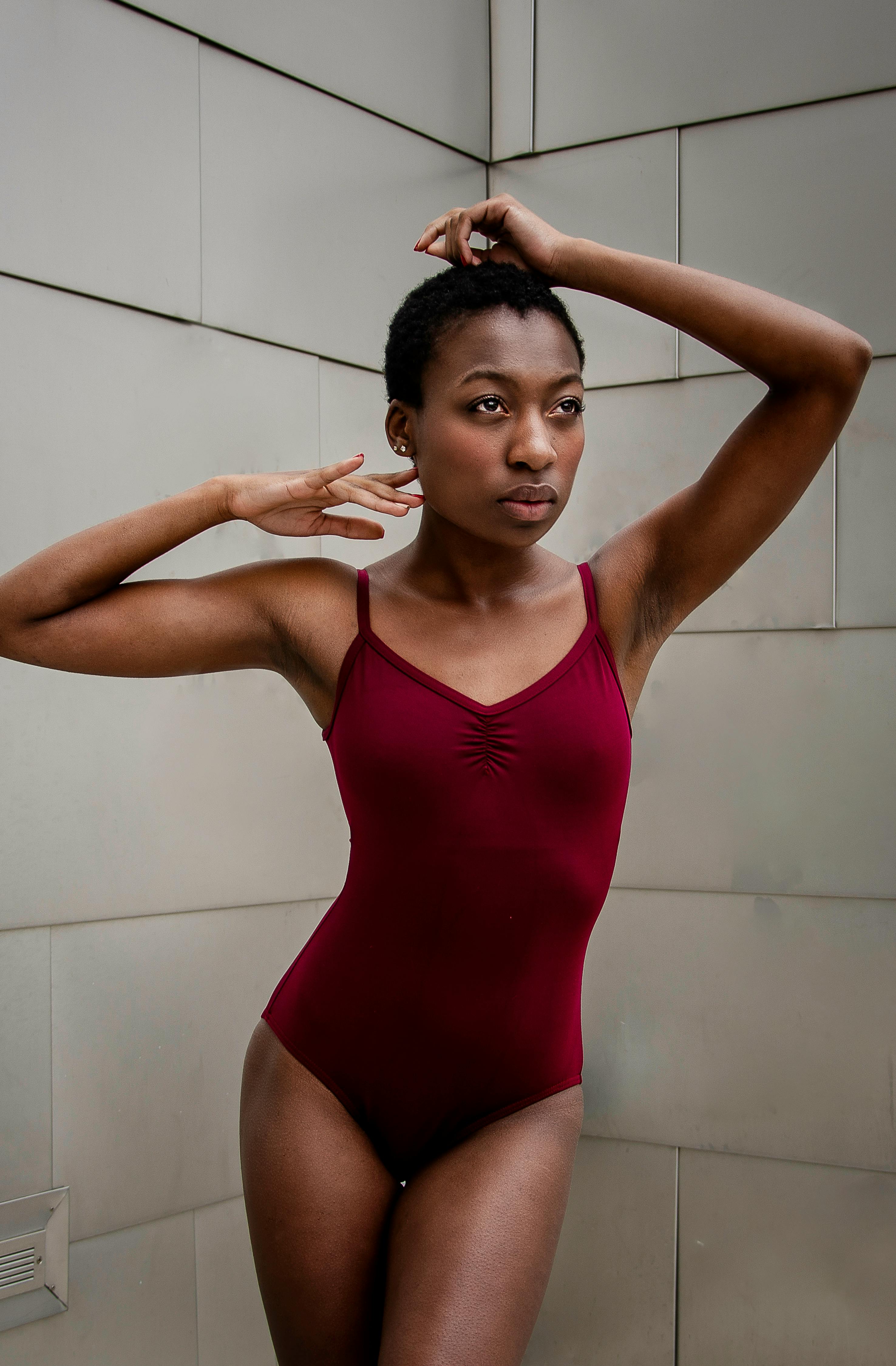 fit young black ballerina standing near tiled wall