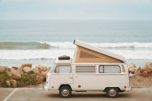 Free A classic camper van parked by a rocky seaside, capturing the essence of coastal travel. Stock Photo