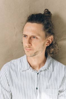 一位穿着条纹衬衫、卷发的成年男子特写肖像，看起来若有所思
