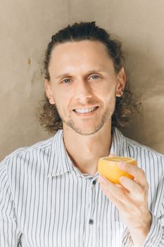 一个穿着条纹衬衫的快乐男人拿着半个橙子，展现着健康的生活方式