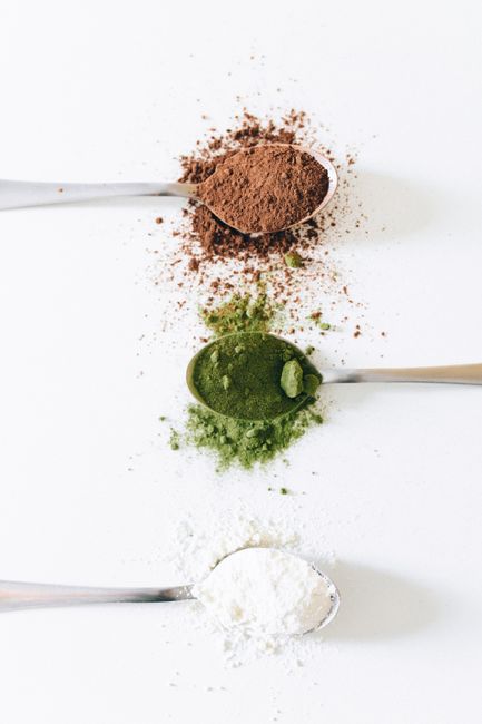 Flat lay of spoons with brown, green, and white powders on a white background. - Evaluating Price vs. Quality in Wellness Products