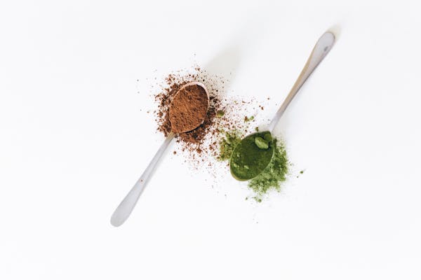 Two spoons with brown and green powder