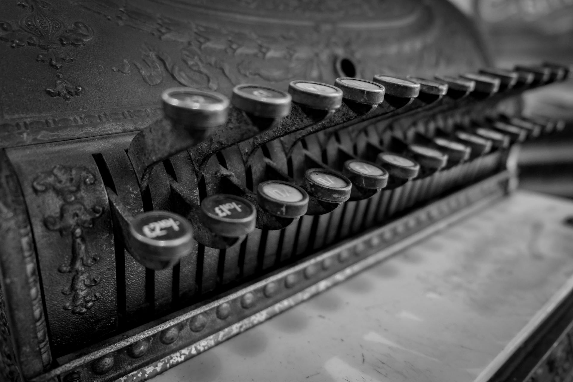 Close-up of an antique cash register in black and white, showcasing vintage details.