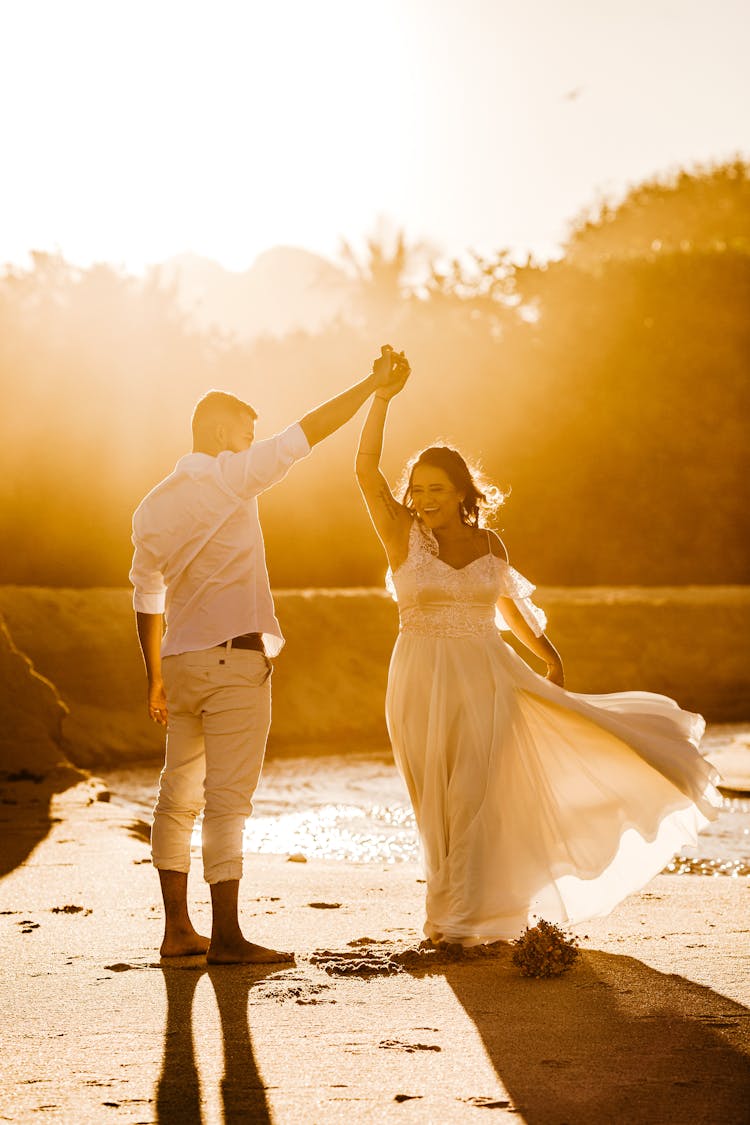 Cheerful Newlywed Couple Dancing On Sandy Coast On Sunny Day