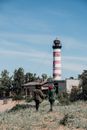 Man in Green Jacket Standing Near Red and White Lighthouse