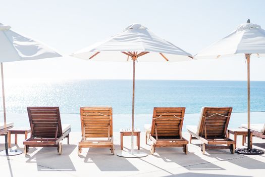 Relaxing beach view with wooden sunloungers and parasols by the ocean.
